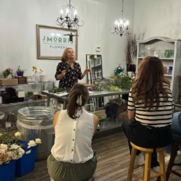 People seated in a flower shop during a floral workshop