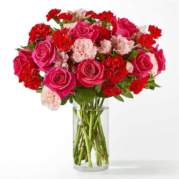 Bouquet of pink roses and red carnations in a clear glass vase
