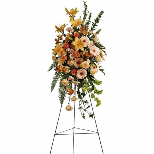 Tall standing spray with yellow lilies, peach roses, and gerbera daisies on a metal easel