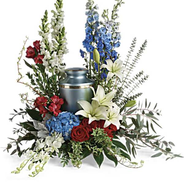 Floral funeral urn arrangement with lilies, roses, and delphinium around a blue urn