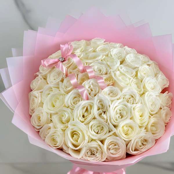 Bouquet of cream roses wrapped in pink paper with a pink ribbon