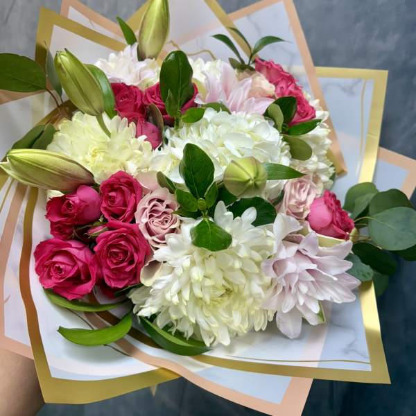 Bouquet of pink roses, white chrysanthemums, and lilies wrapped in pastel paper