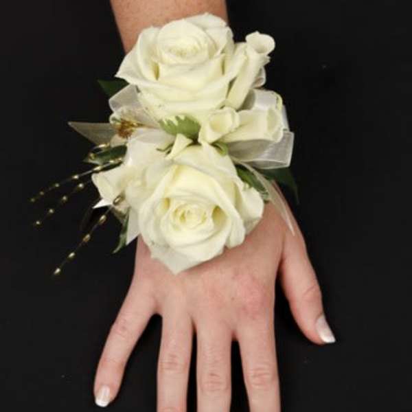 White rose wrist corsage with ribbon on a hand