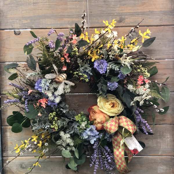 Colorful floral wreath with yellow, purple, and peach blooms on a wood background