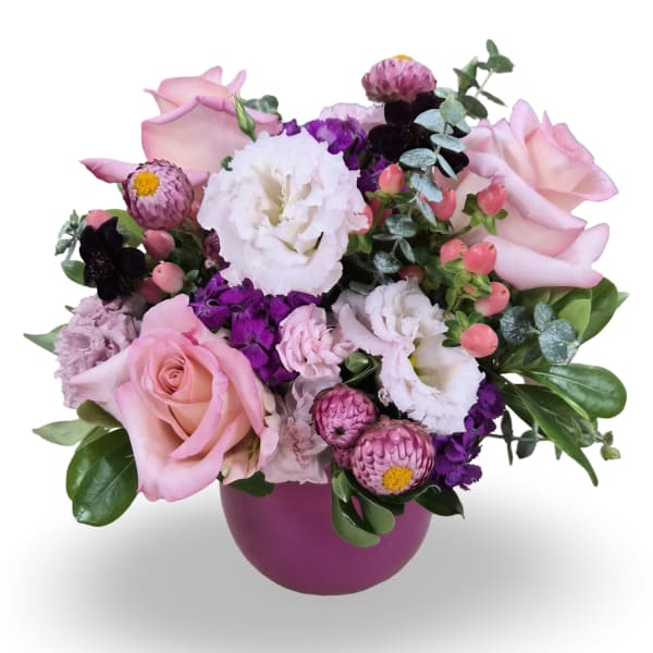 Pink roses and white blooms arranged in a purple vase