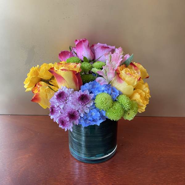 Colorful bouquet of roses, hydrangeas, and chrysanthemums in a glass vase