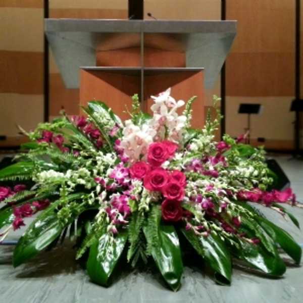 Large pink and white floral arrangement displayed in front of a podium on a stage