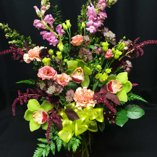 Mixed bouquet of pink and green flowers in a glass vase with a ribbon