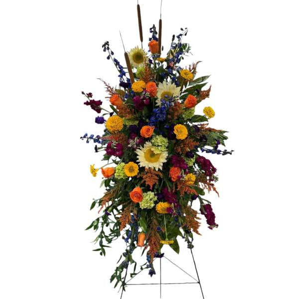 Tall standing floral spray with sunflowers, roses, and mixed blooms on an easel