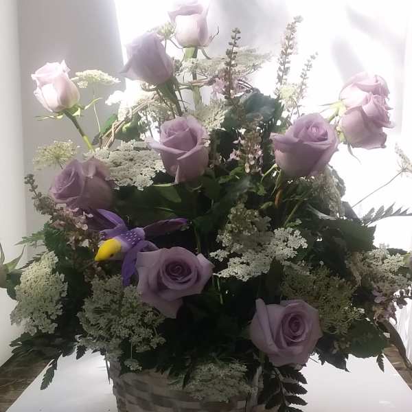 Lavender roses in a woven basket with white filler flowers