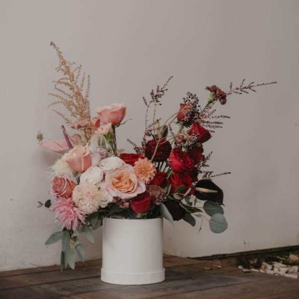 Pink and red rose arrangement in a white cylindrical vase