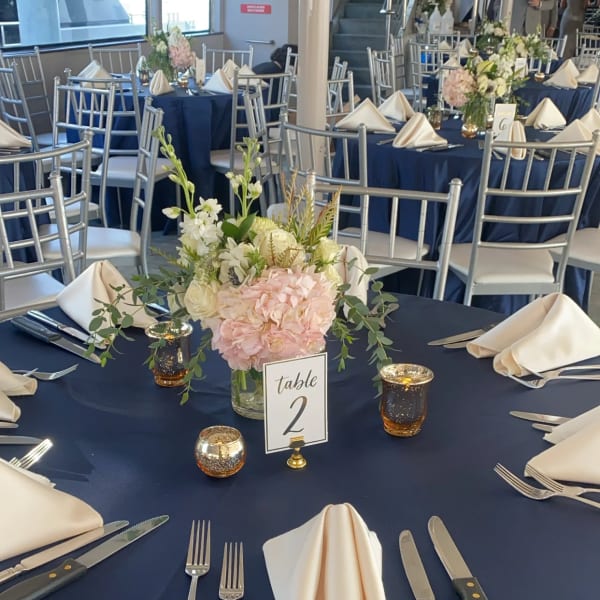Floral centerpiece on a navy-draped table with folded cream napkins
