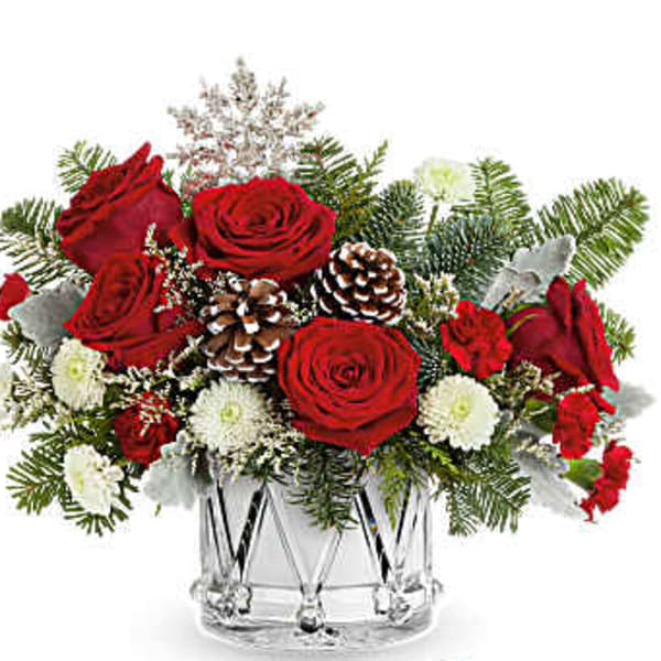 Red roses and white flowers in a clear glass vase with pinecones