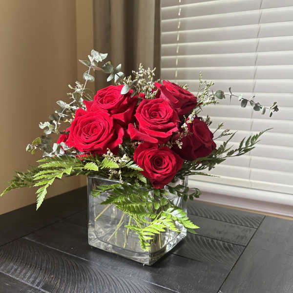 Red roses arranged in a clear square glass vase