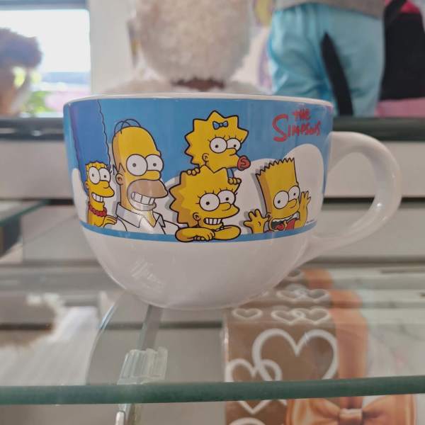 The Simpsons mug with a white handle on a glass shelf