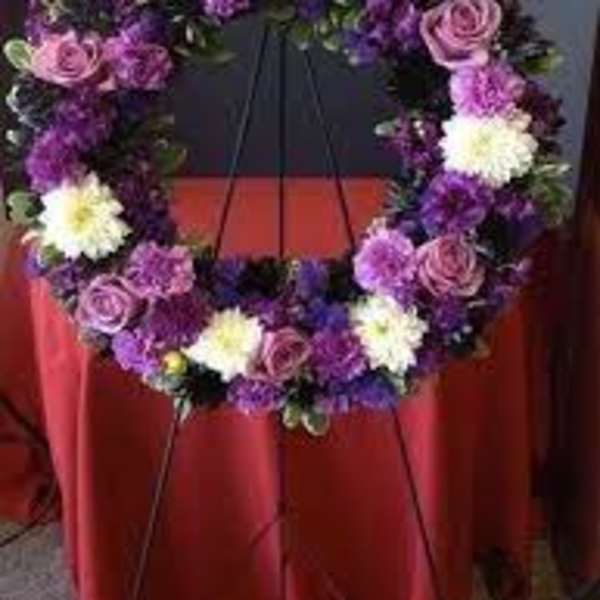 Purple and white floral wreath on a stand