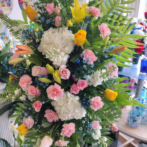 Tall mixed floral standing arrangement with pink, white, and yellow blooms