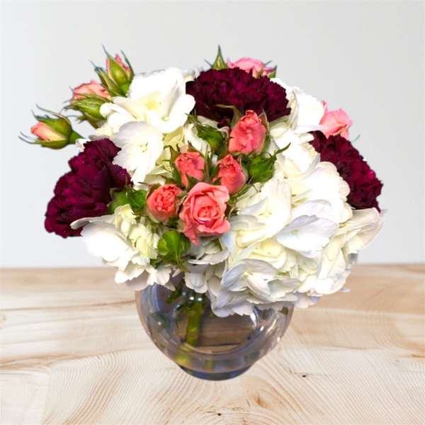 Bouquet of white and pink flowers in a round glass vase