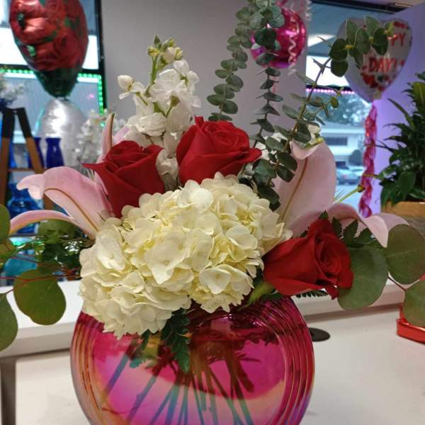 Bouquet of red roses and white hydrangeas in a pink glass vase