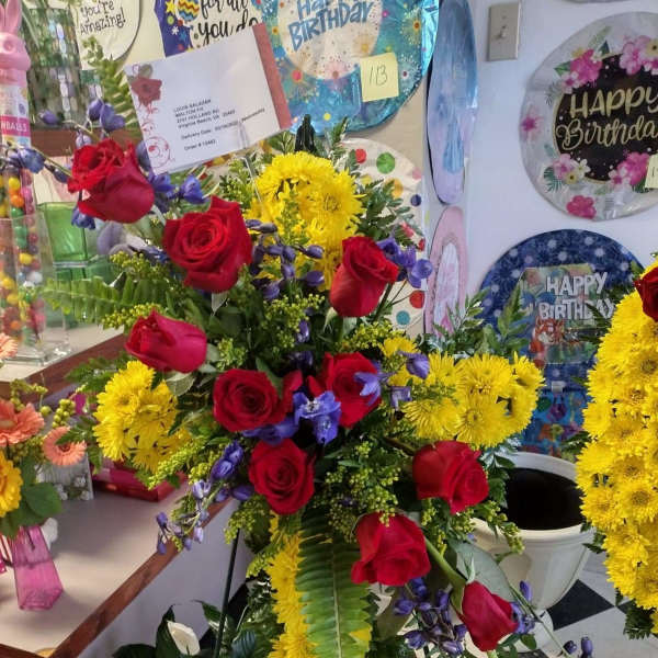 Tall floral spray with red roses, yellow chrysanthemums, and purple accents