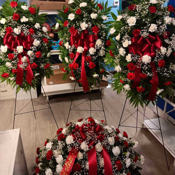 Three standing floral wreaths with red and white flowers and red ribbons