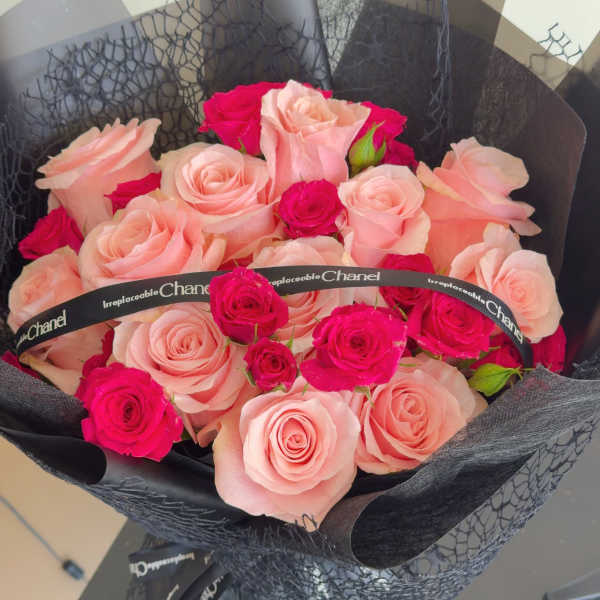 Bouquet of pale pink and hot pink roses wrapped in black paper