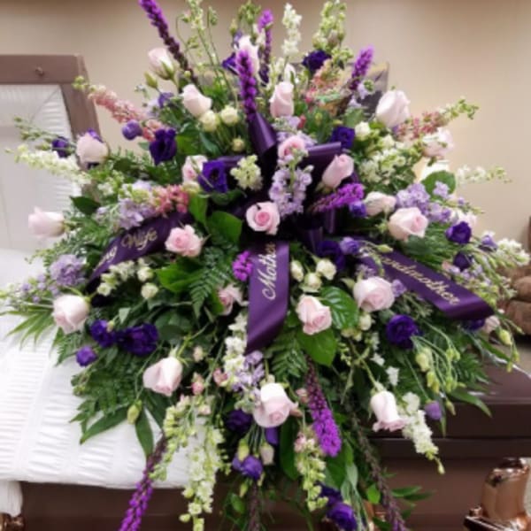Large purple and pink funeral spray on a casket