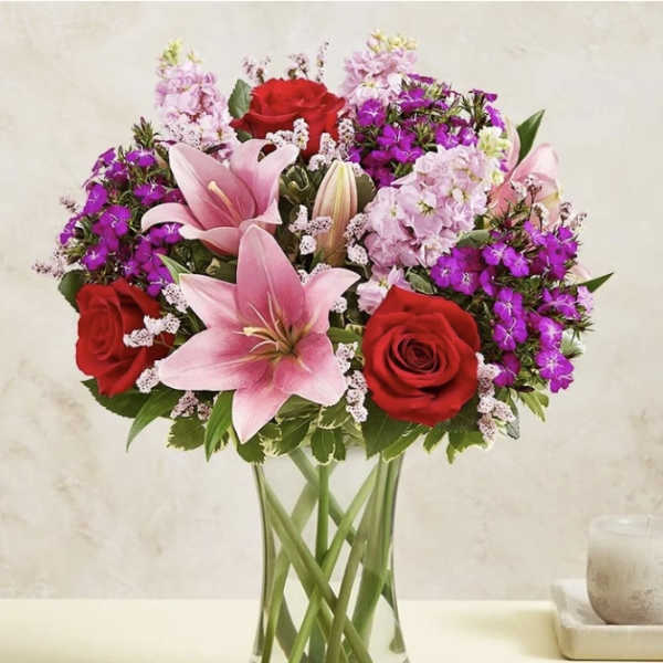 Bouquet of pink lilies and red roses in a clear glass vase