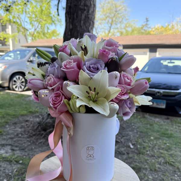 Pink roses and white lilies arranged in a white hatbox with ribbon