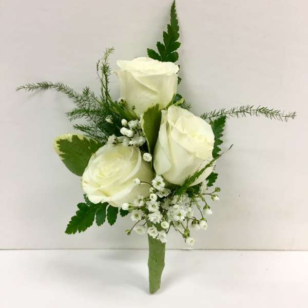 White rose boutonniere with small white filler flowers and greenery