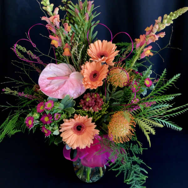 Colorful floral arrangement with pink anthurium and peach gerbera daisies in a glass vase