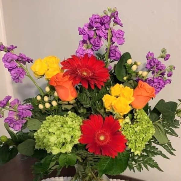 Colorful mixed bouquet in a clear glass vase with gerbera daisies and roses