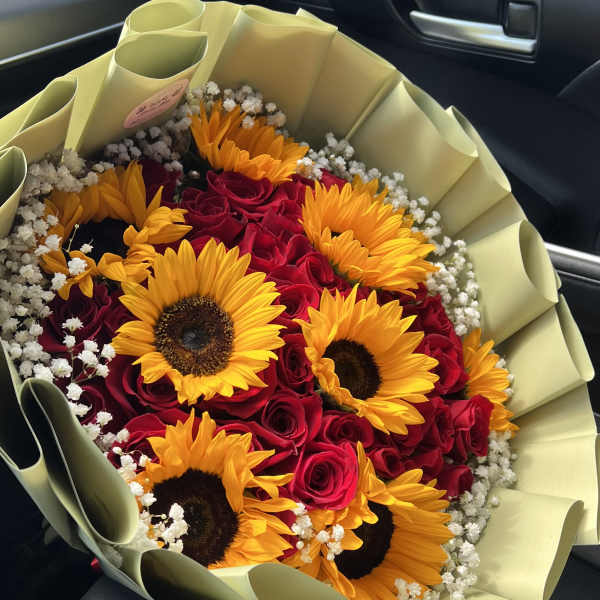 Bouquet of red roses and yellow sunflowers wrapped in pale paper