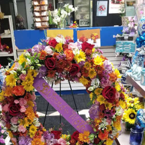 Large circular floral wreath on an easel with a purple ribbon