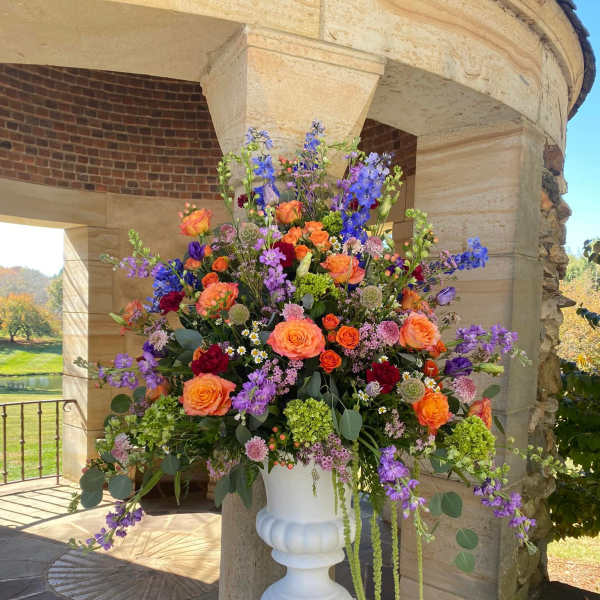 Large colorful floral arrangement in a white pedestal vase