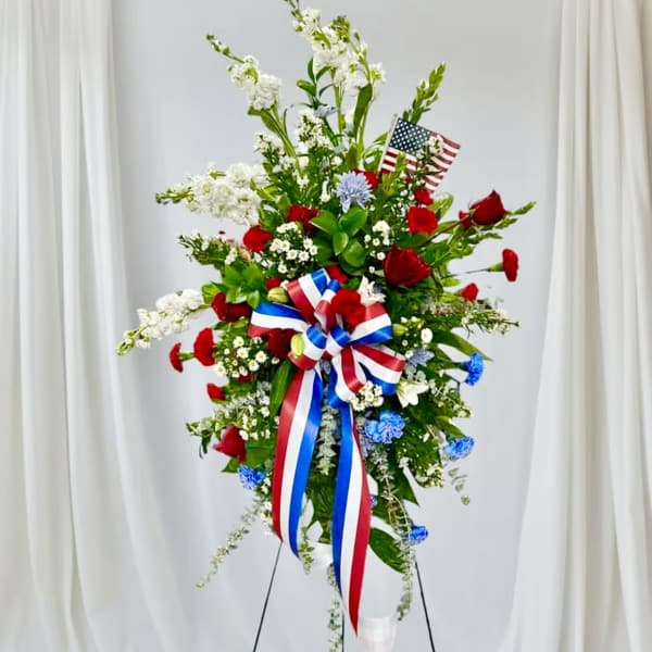 Standing floral spray with red, white, and blue flowers and ribbons