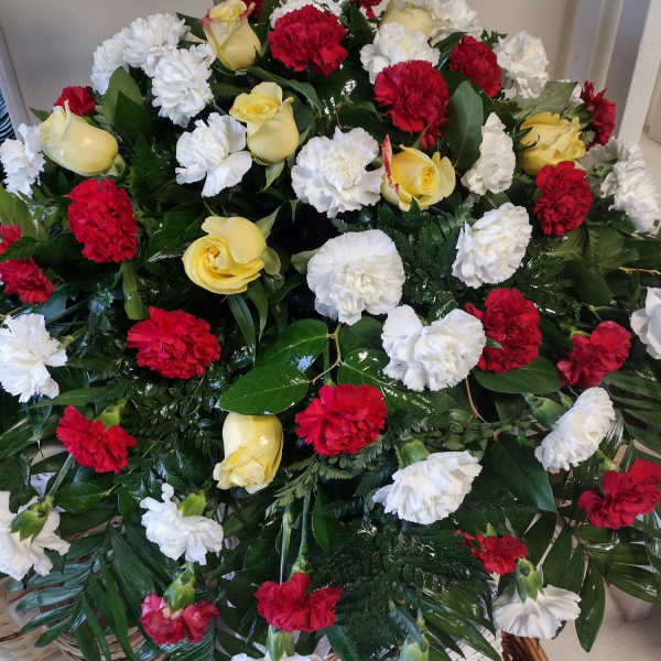 Casket spray with red, white, and yellow flowers