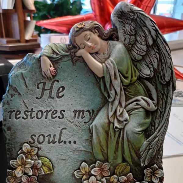 Decorative angel figurine leaning on a stone plaque with flowers