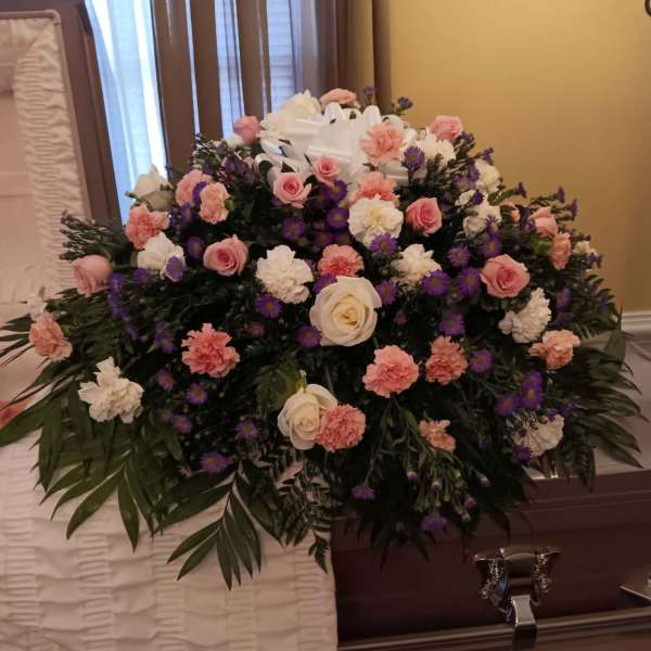 Large funeral casket spray with pink, white, and purple flowers