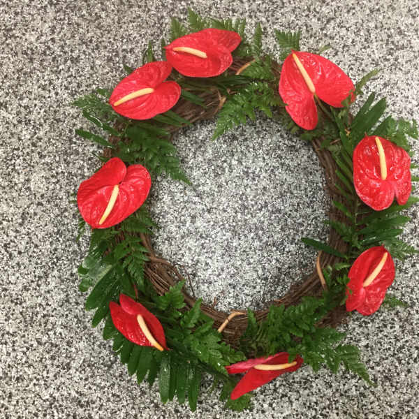 Red floral wreath with green foliage on a speckled gray surface