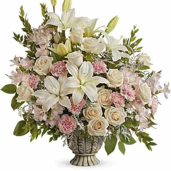 Arrangement of white lilies, pale roses, and pink carnations in a decorative vase