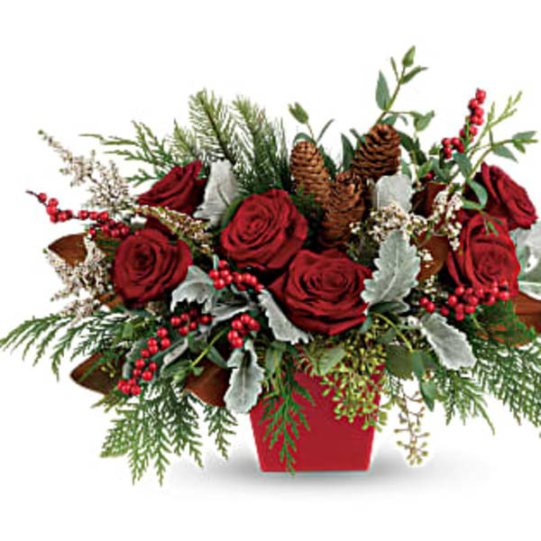 Red roses in a red container with pinecones and berries