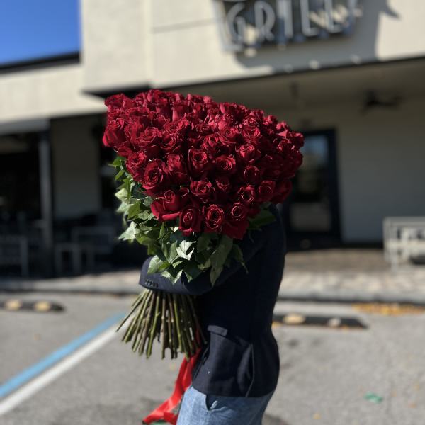Large bouquet of deep red roses with a red ribbon wrap