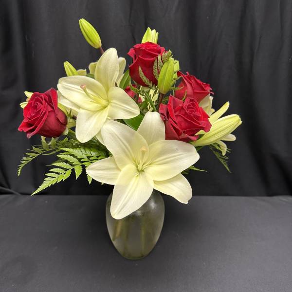Red roses and white lilies arranged in a glass vase
