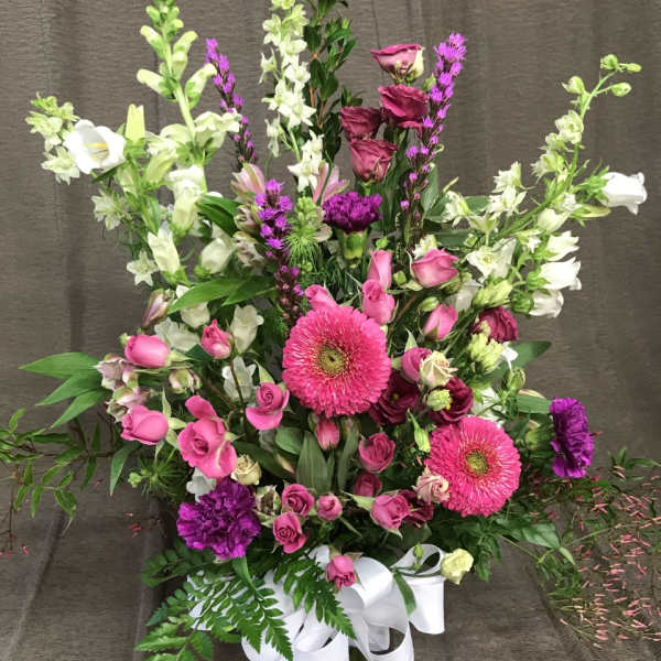 Pink and white mixed flower arrangement in a glass vase with a white ribbon