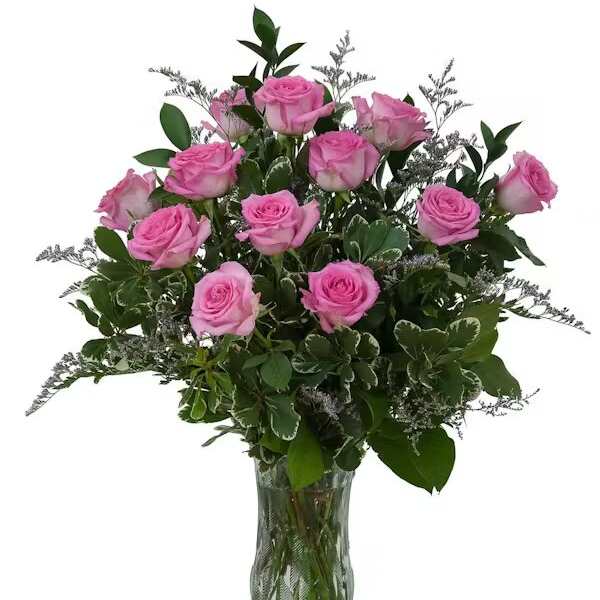 Pink roses arranged in a clear glass vase with greenery