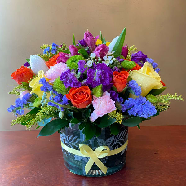 Colorful mixed bouquet in a glass vase with a yellow ribbon