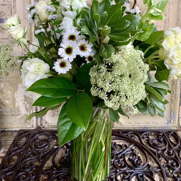 White flowers and greenery arranged in a clear glass vase