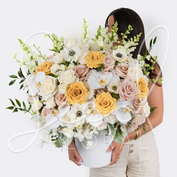Large bouquet of white, blush, and yellow flowers in a white vase