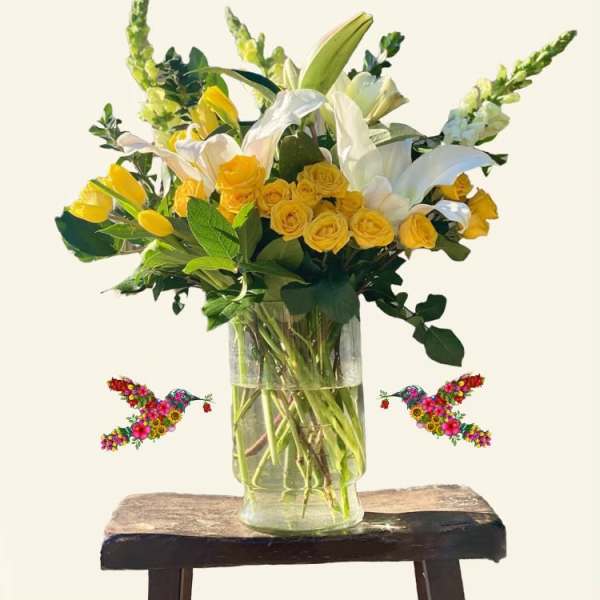 Yellow roses and white lilies in a clear glass vase